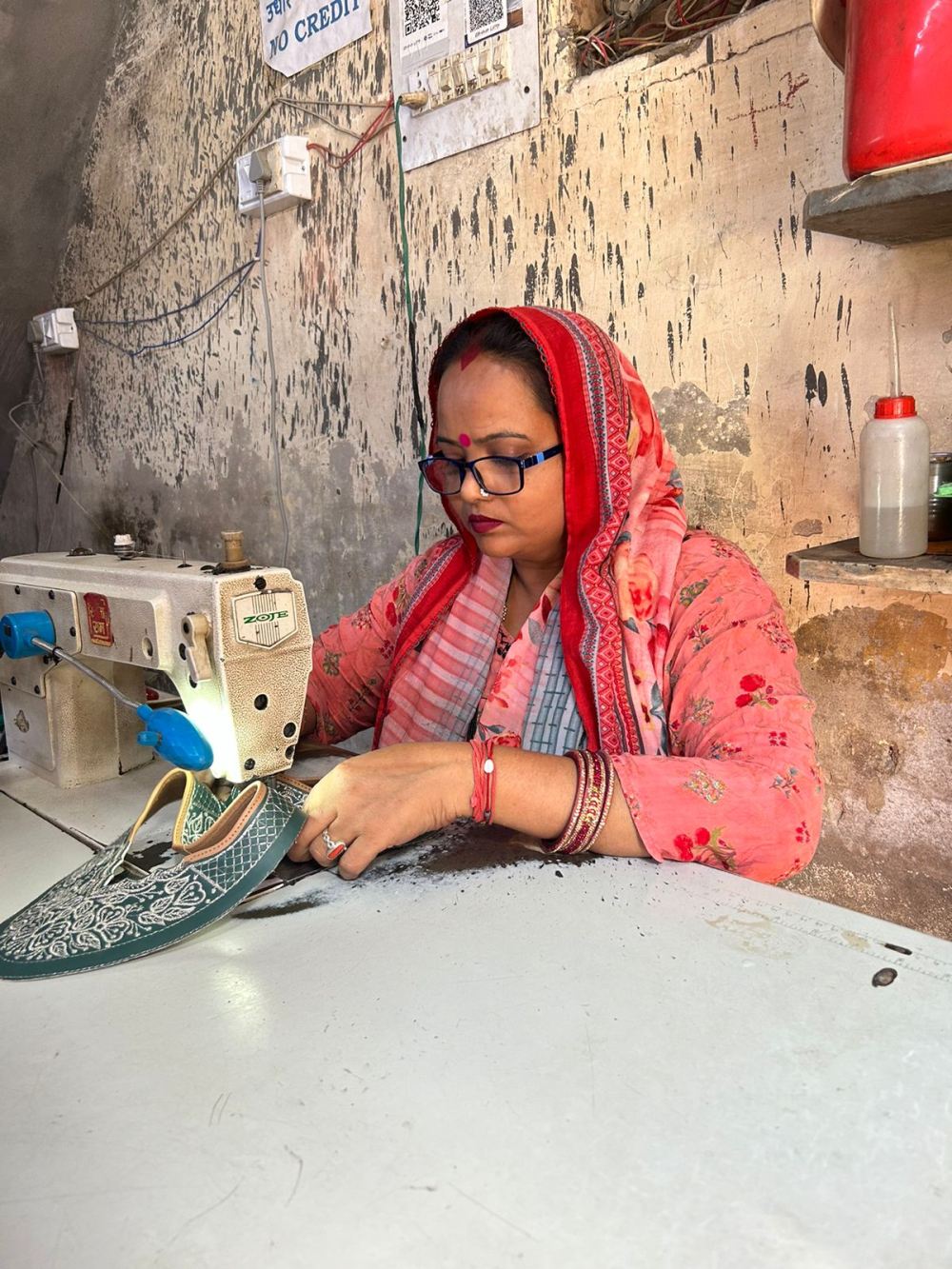 Inside the craftsman’s home, his wife pipes the jutti uppers on a sewing machine with remarkable speed and precision. (Picture Credits: Nandini Agarwal)