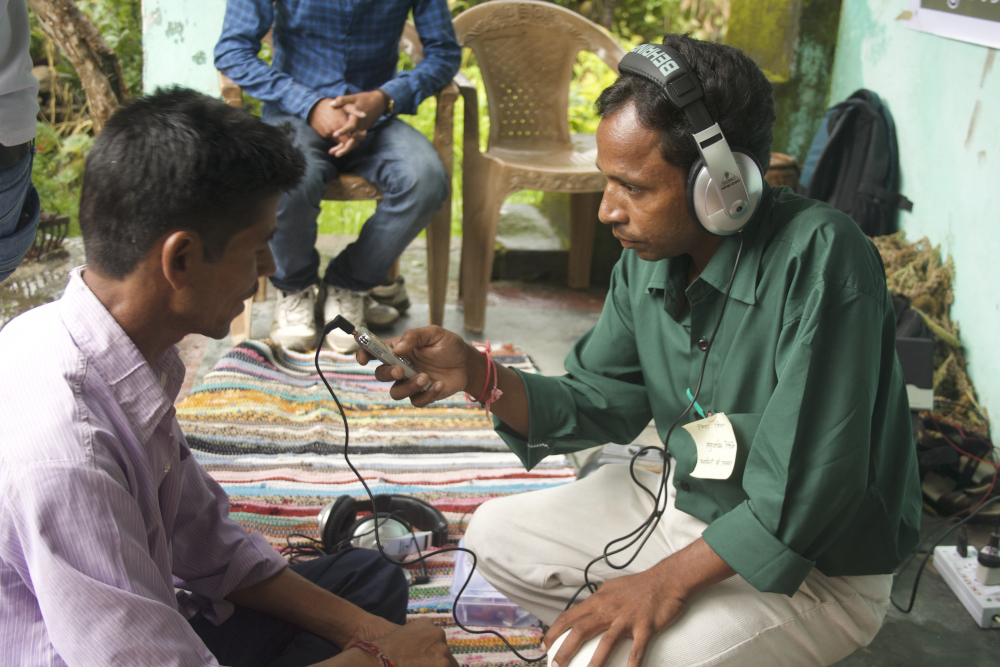 Fig. 2: Former team member of Mandakini ki Awaaz, Ramesh Rangeela, records a community member’s message in Jaikhandi. In Mandakini river valley, most villages are not easily accessible; team members from Mandakini ki Awaaz usually organise field visits to villages in their catchment community to speak to community members about relevant issues and record artistes and musicians. These field visits provide musicians who may not be able to physically travel to the community radio station an opportunity to have their music recorded and showcased on the radio (Photograph by Shweta Radhakrishnan/ Courtesy: People’s Power Collective)