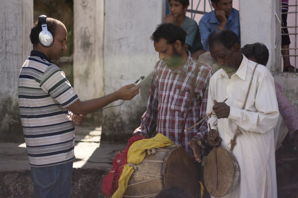 Fig. 3: Manvendra Singh Negi, founder of community radio, Mandakini ki Awaaz, records dhol damaun players in the village of Basti. Collectively called dhol damaun, they are percussion folk music instruments made of copper, wood, and animal hide, and are considered auspicious in the region. They are played for a variety of occasions ranging from social gatherings, weddings, and religious functions and rituals (Photograph by Shweta Radhakrishnan/ Courtesy: People’s Power Collective)