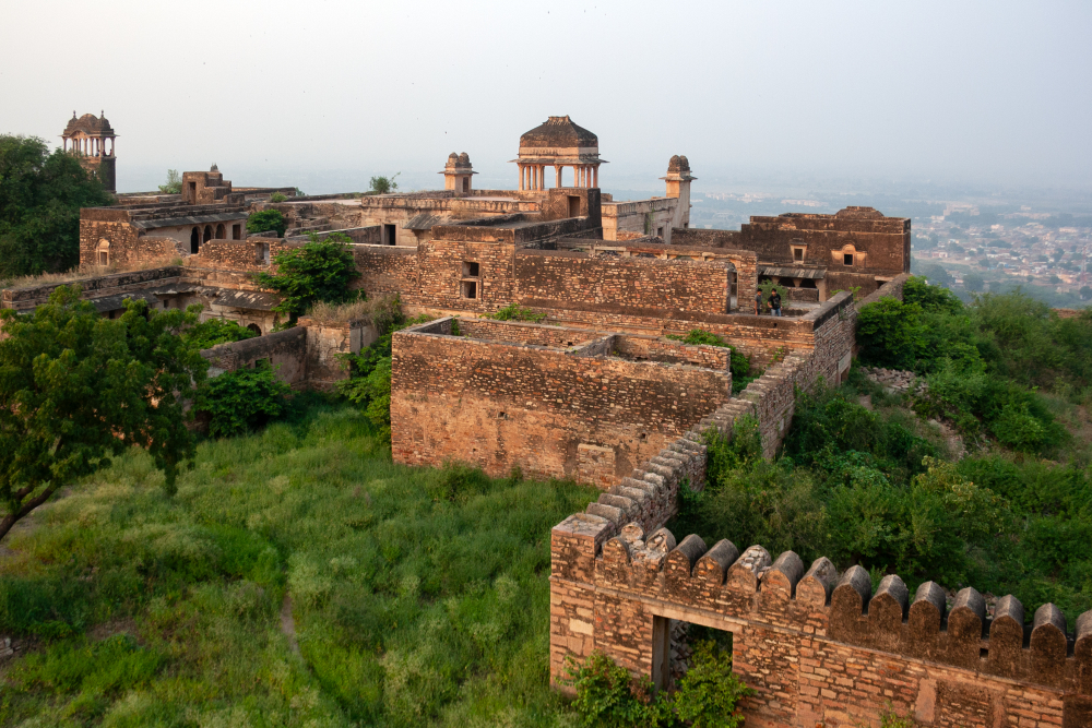Palace ruins at Gwalior Fort, including residential courtyards, pavilions, defensive walls, and bastions, built of sandstone and masonry, overlooking the surrounding cityscape from above. (Picture Credits: Ayan Ghosh)