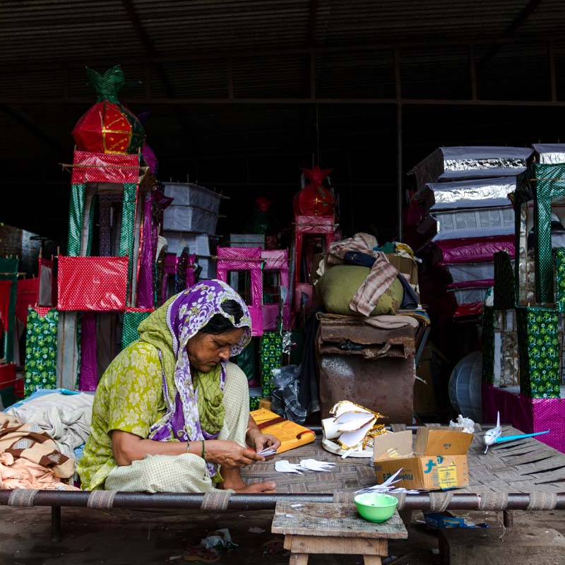 An old woman making kamrakhi gumzi (starfruit dome) sitting next to stacked bamboo taziya parts in Kazmain, a religious monument in Saadatganj, Lucknow. The kamrakhi gumzi is atop the taziya and is a unique feature of Lucknow's taziya (Courtesy: Aoun Hasan)