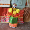 A laidhibi wearing a potloi, a green cylindrical skirt-like wrap. The red net worn around the waist is call boswan. Laces, trimmings, beads and artificial flowers are used to decorate the laidhibi (Courtesy: Akoijam Sunita)