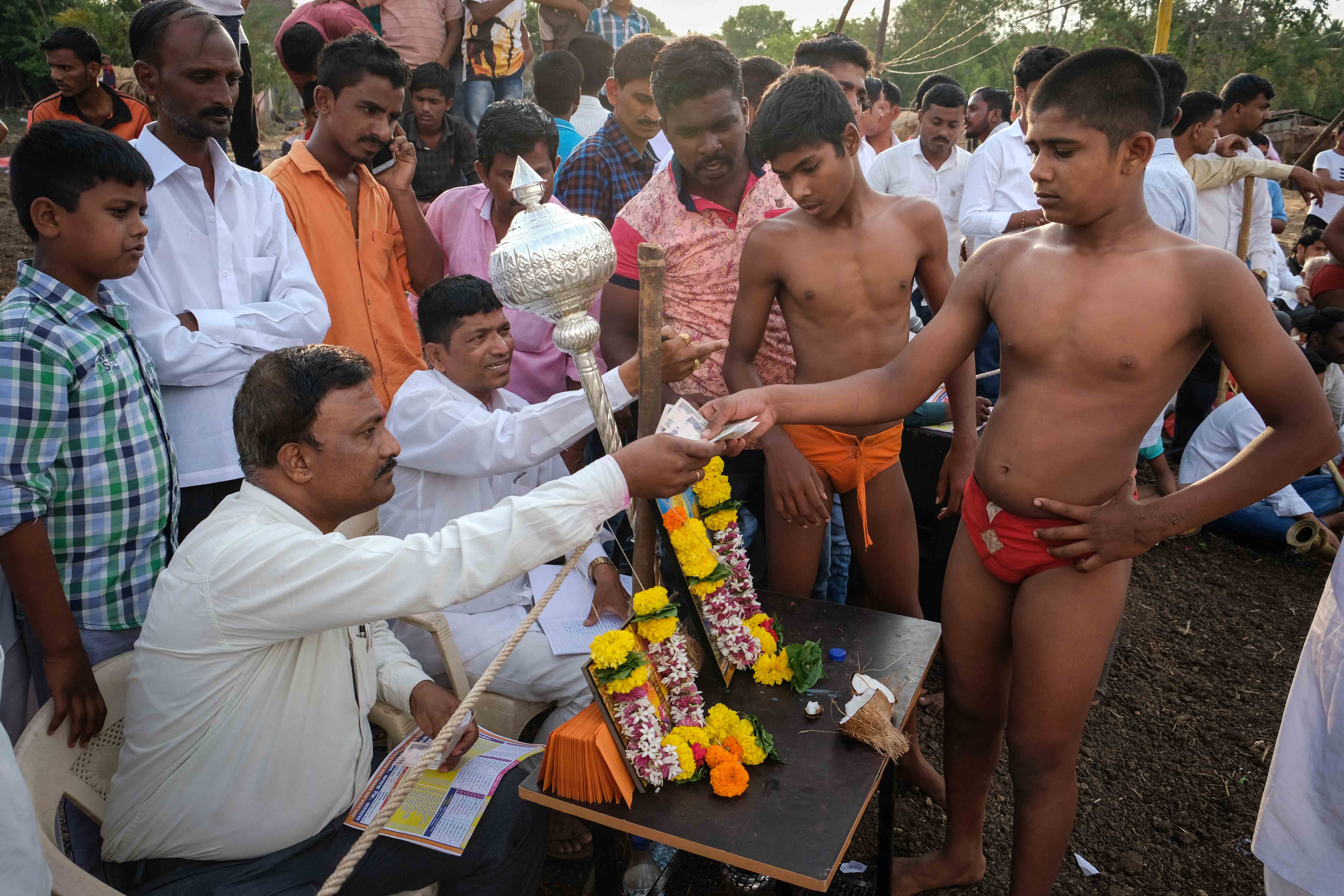 Wrestlers receiving their prize money at a local competition held in Savade village, Karad taluka of Satara district in Maharashtra. Prize amount can be anything between 150 rupees to 1 lakh rupees, depending on the different weight categories, age groups and the various finishing positions. Photograph by Indrajit Khambe ©Sahapedia 