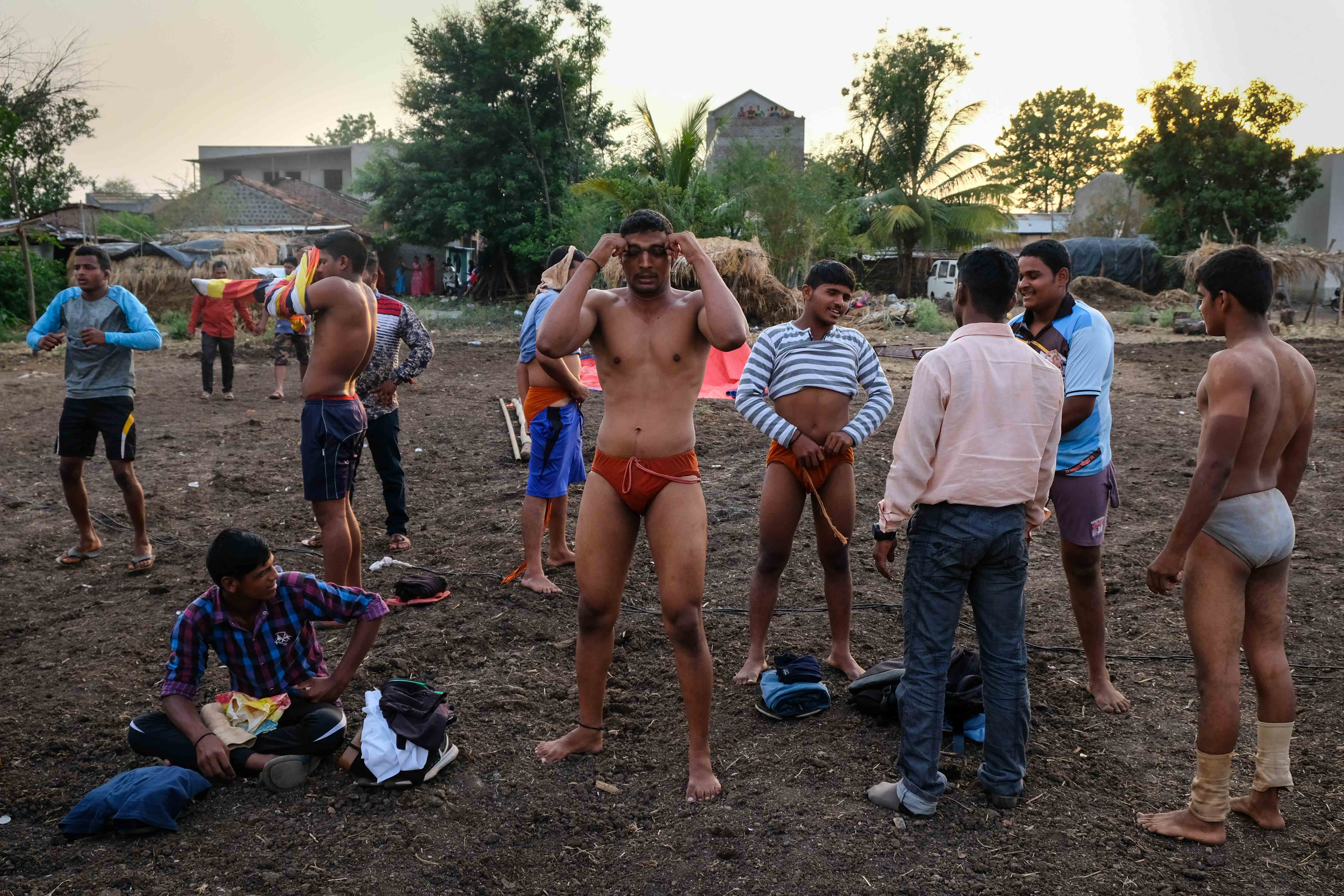 Wrestlers from various villages getting ready before a competition. Such village tournaments are held with minimal arrangements. Participants change their costumes in the open and do a long session of warm-up before each bout. Photograph by Indrajit Khambe ©Sahapedia