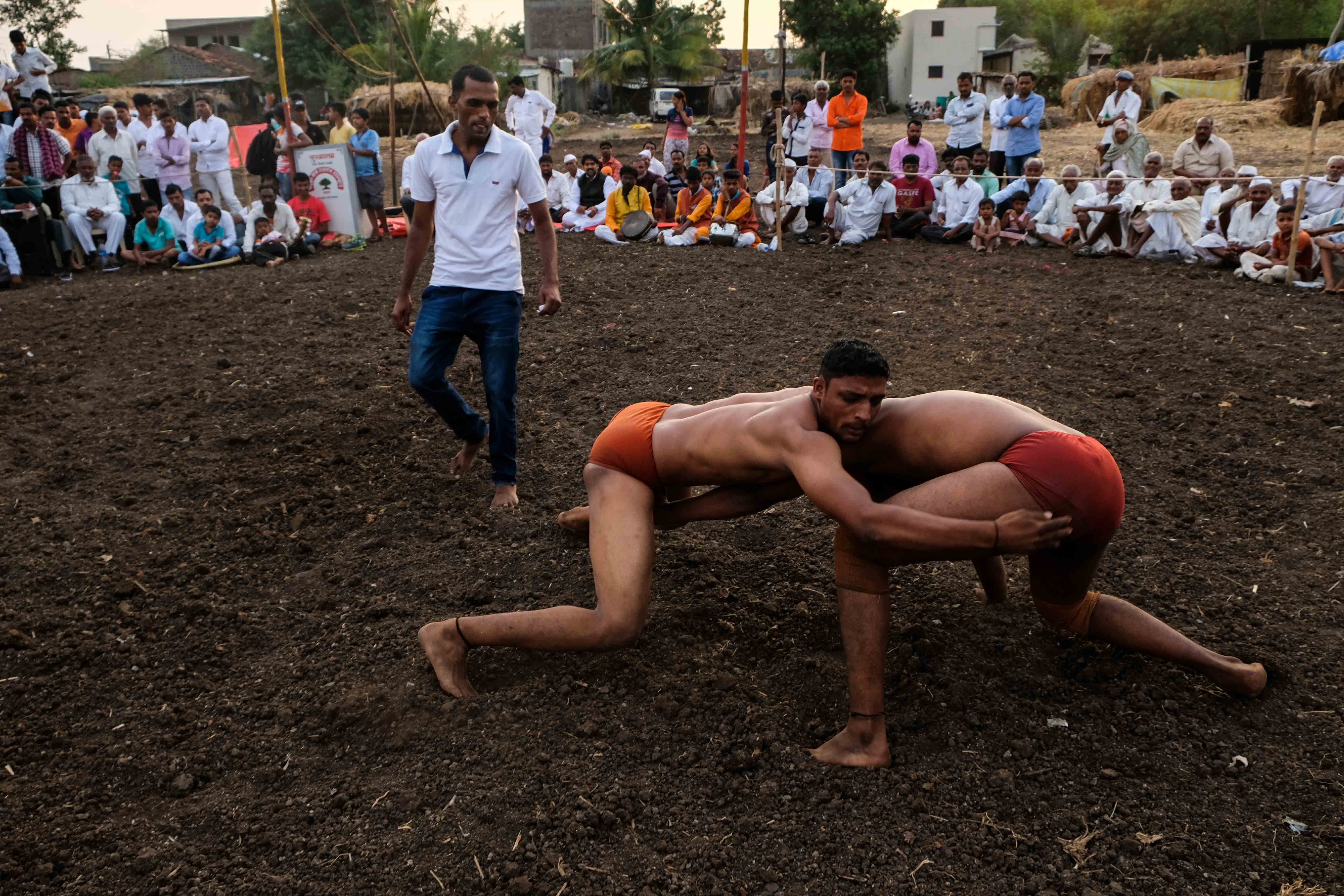 Intense moment from a fight held in Savade village of Satara district in Maharashtra. Grapplers struggle to grasp their opponent and pin them down to score a point. Unlike international or national tournaments, there is no restriction of time at the village-level tournaments and bouts can last long. Photograph by Indrajit Khambe ©Sahapedia