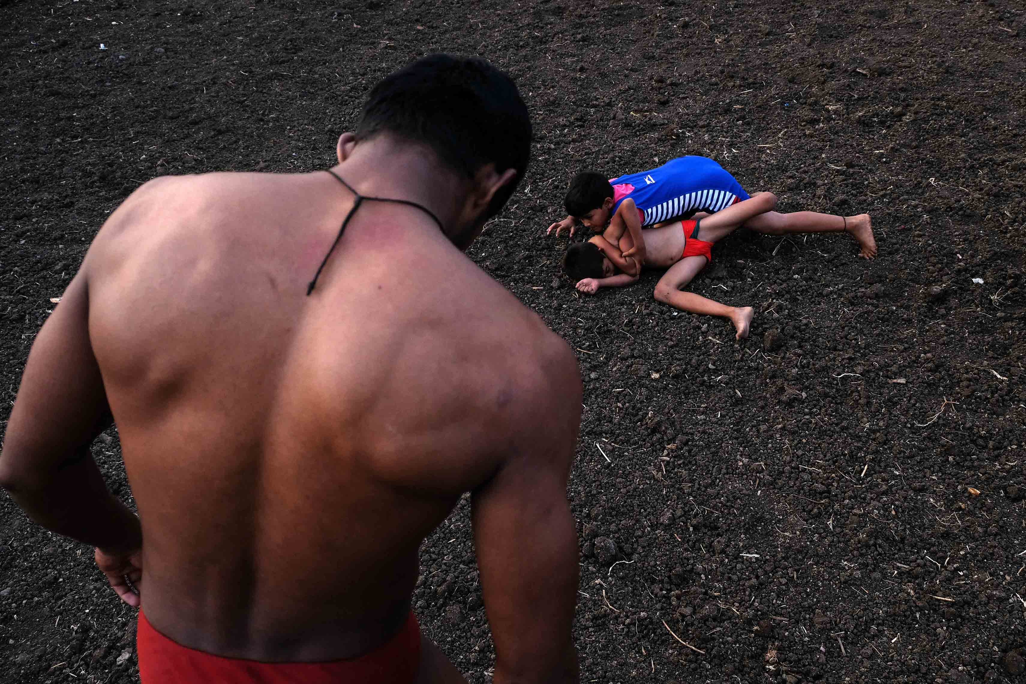  Eight-year-old Sairaj Shelke (in red langot) and 7-year-old girl Gautami Chorge (blue tracksuit) fighting for a championship title in Savade village. Till a few years back, women were prohibited from wrestling. But now the scenario has changed, especially after the success of the Bollywood movie 'Dangal' which was based on the real-life story of the Phogat sisters from Haryana. Photograph by Indrajit Khambe ©Sahapedia 