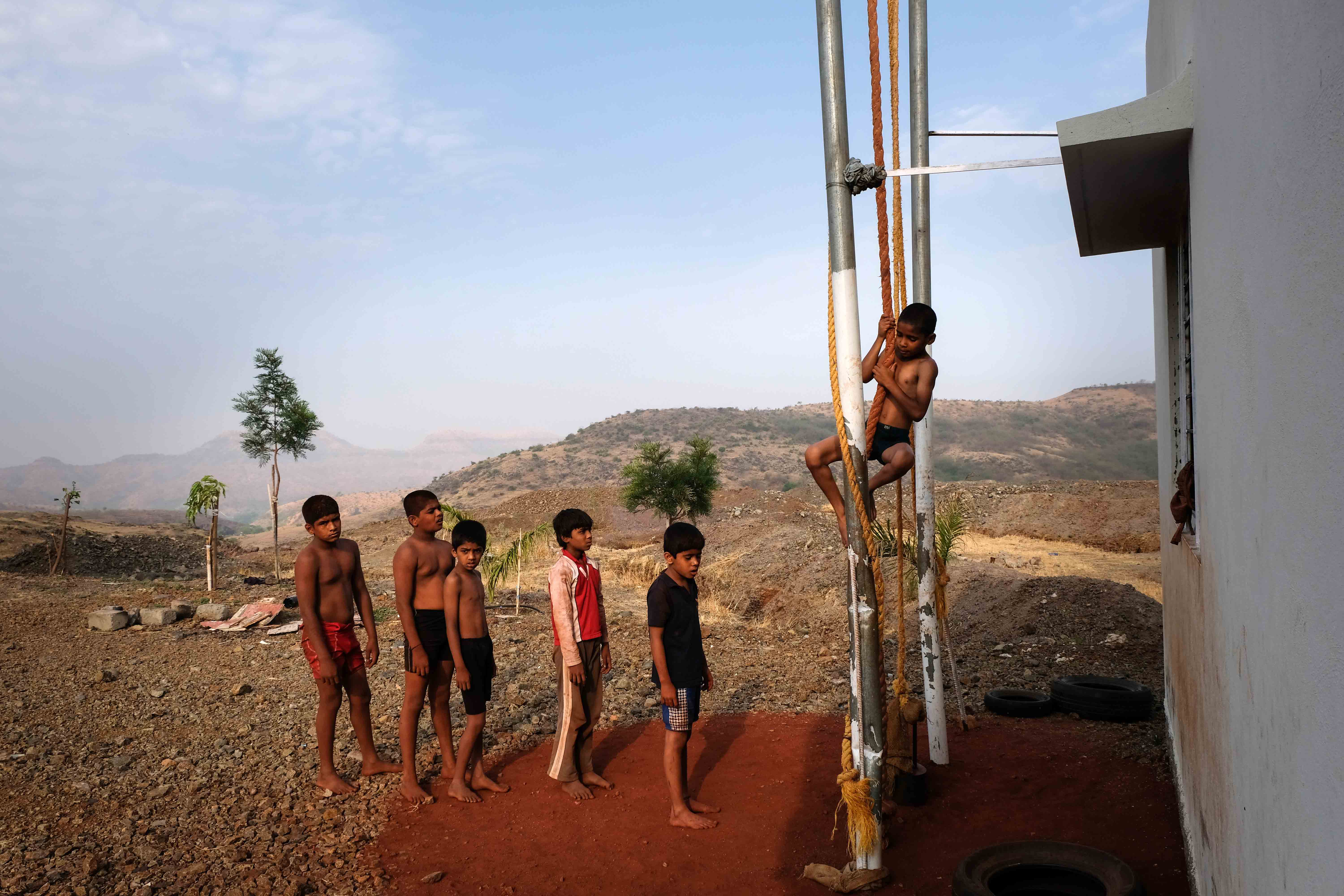 Trainee wrestlers from Surli village waiting for their turn in climbing the rope. They usually do this exercise 50 times in every session. Rope climbing is beneficial for powerlifters, gymnasts, wrestlers, strongmen and weightlifters. This exercise requires minimum equipment and forms a regular aspect of training at the akharas. Photograph by Indrajit Khambe ©Sahapedia