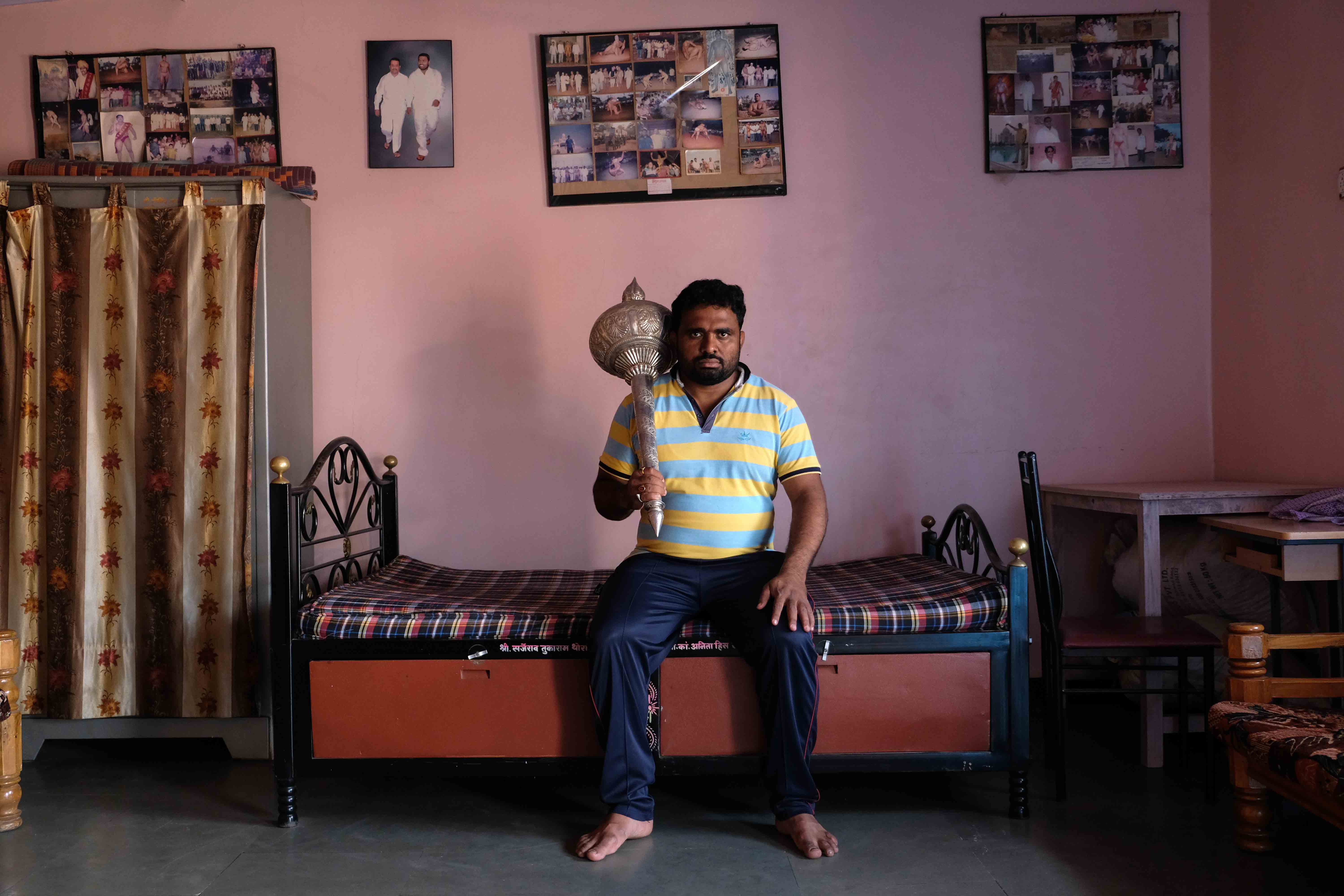 Portrait of Santosh Vetal (aged 38) at his home. Vetal won the Hind Kesari title in 2014 which is the most prestigious award in Indian wrestling. He lives in Surli village of Satara district in Maharashtra. The silver mace (gada) which he is holding is the prize he won for winning the Hind Kesari title. Gada is the primary weapon of Lord Hanuman and is presented as a trophy to winners of wrestling competitions in India. Photograph by Indrajit Khambe ©Sahapedia 