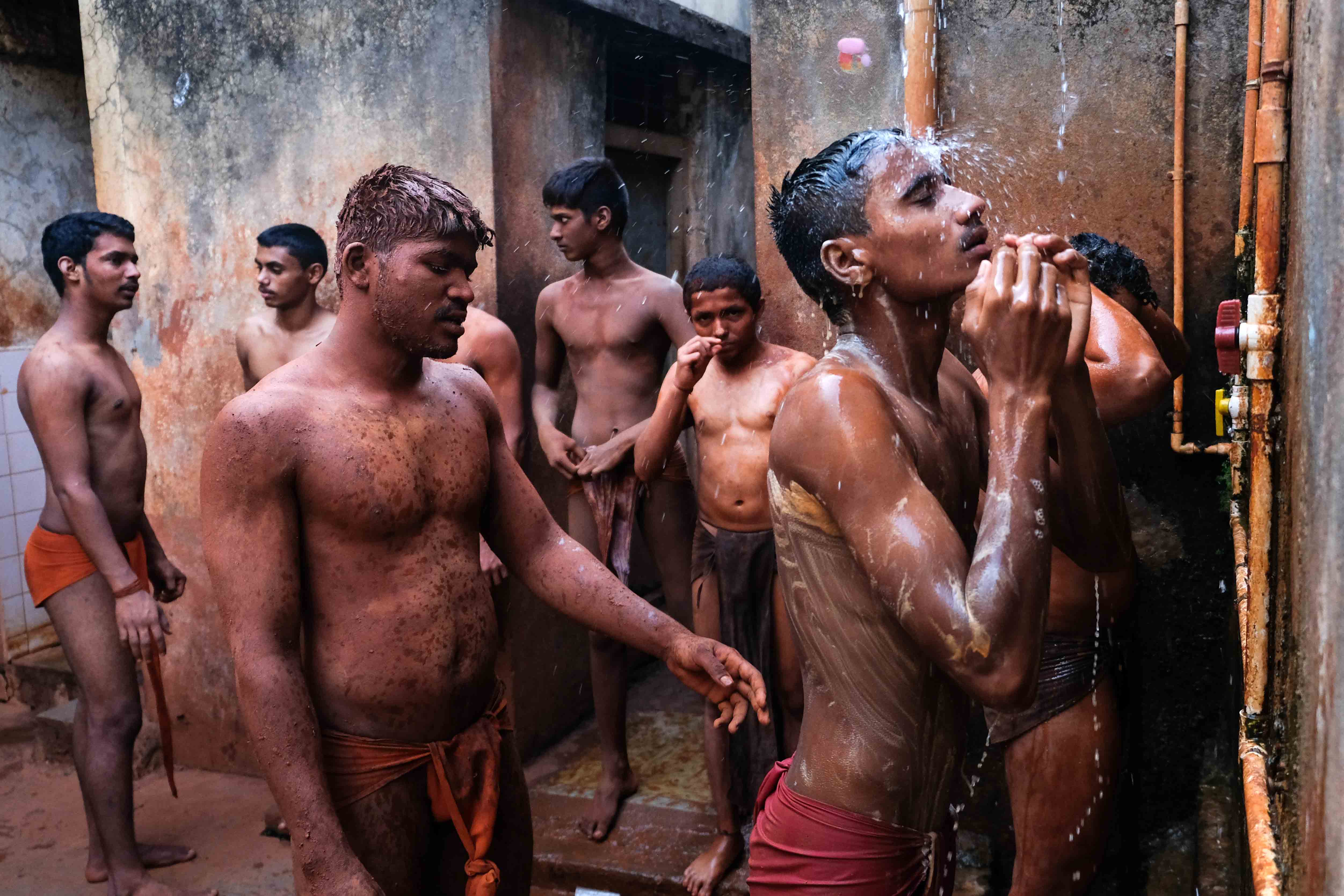 Wrestlers cool under a shower in Motibag Akhara, Kolhapur. There is no concept of privacy; at the end of the training session, the wrestlers bathe in the open. While taking bath, pehelwans help each other in cleaning and scrubbing off the soil and sweat gathered during the training session. Photograph by Indrajit Khambe ©Sahapedia