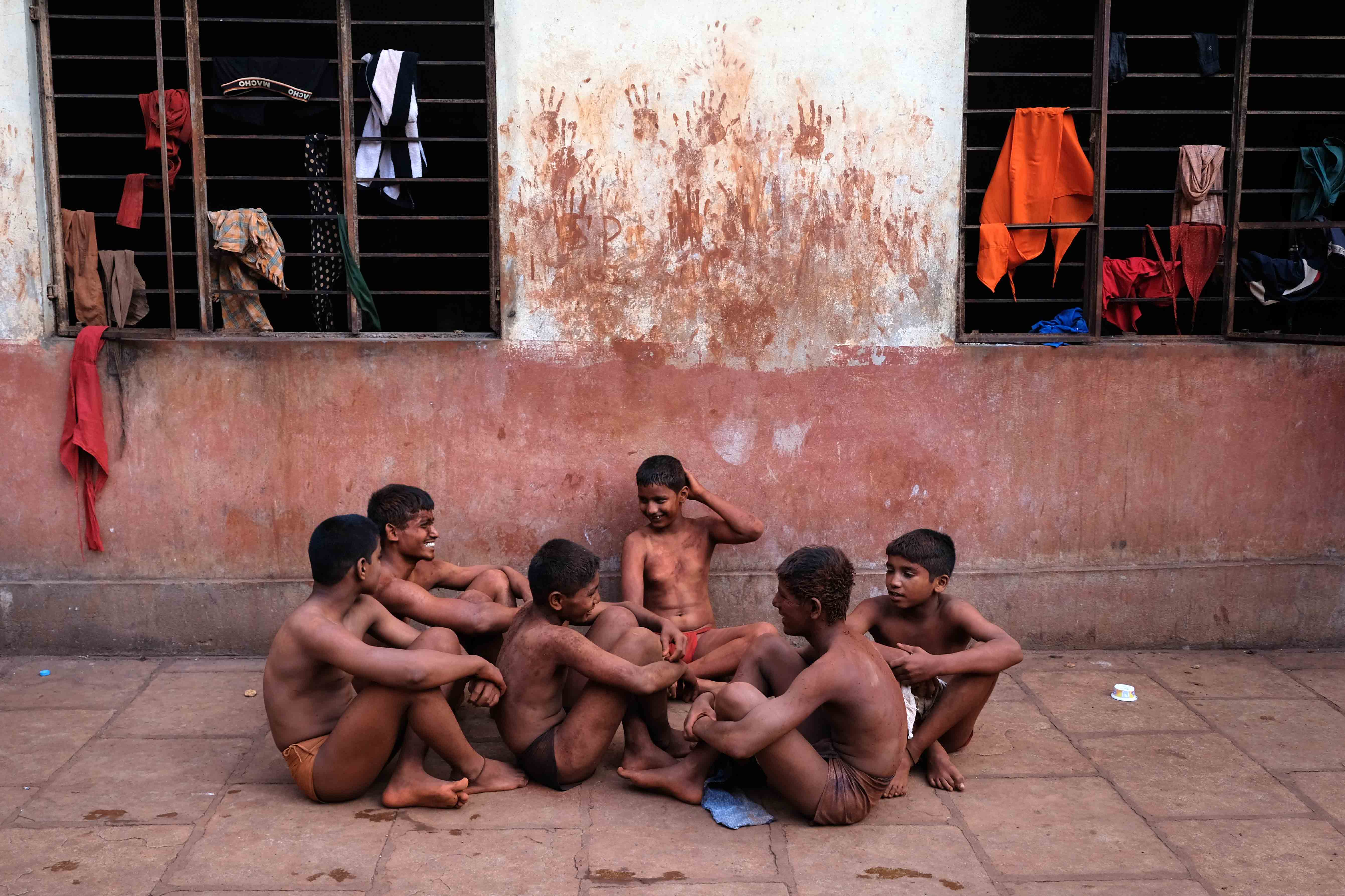 A group of young wrestlers waiting for their turn to take a bath after the senior pehelwans. Taking a bath together following the training sessions is a daily ritual; it concludes the morning session after which breakfast is prepared. Photograph by Indrajit Khambe ©Sahapedia