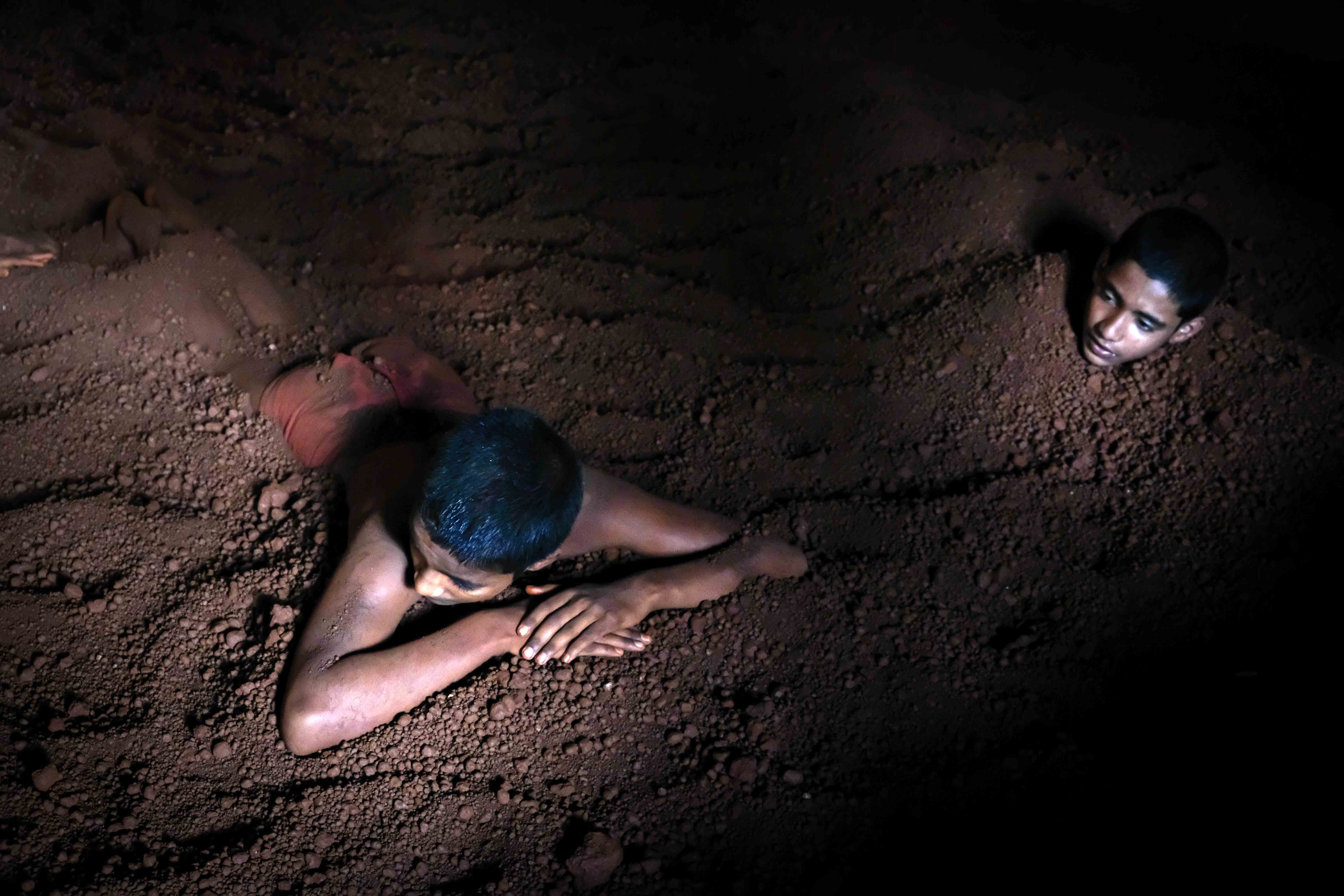 Young wrestlers cover their body with the soil of the training arena of Motibag Akhara. Preparation of the soil before dangal is an important ritual in all akharas. The soil is mixed with turmeric, milk, ghee, buttermilk and other natural ingredients which have curative properties. This mixture not only makes the soil soft and conducive for wrestling, but also has benefits when applied to naked skin. Photograph by Indrajit Khambe ©Sahapedia 