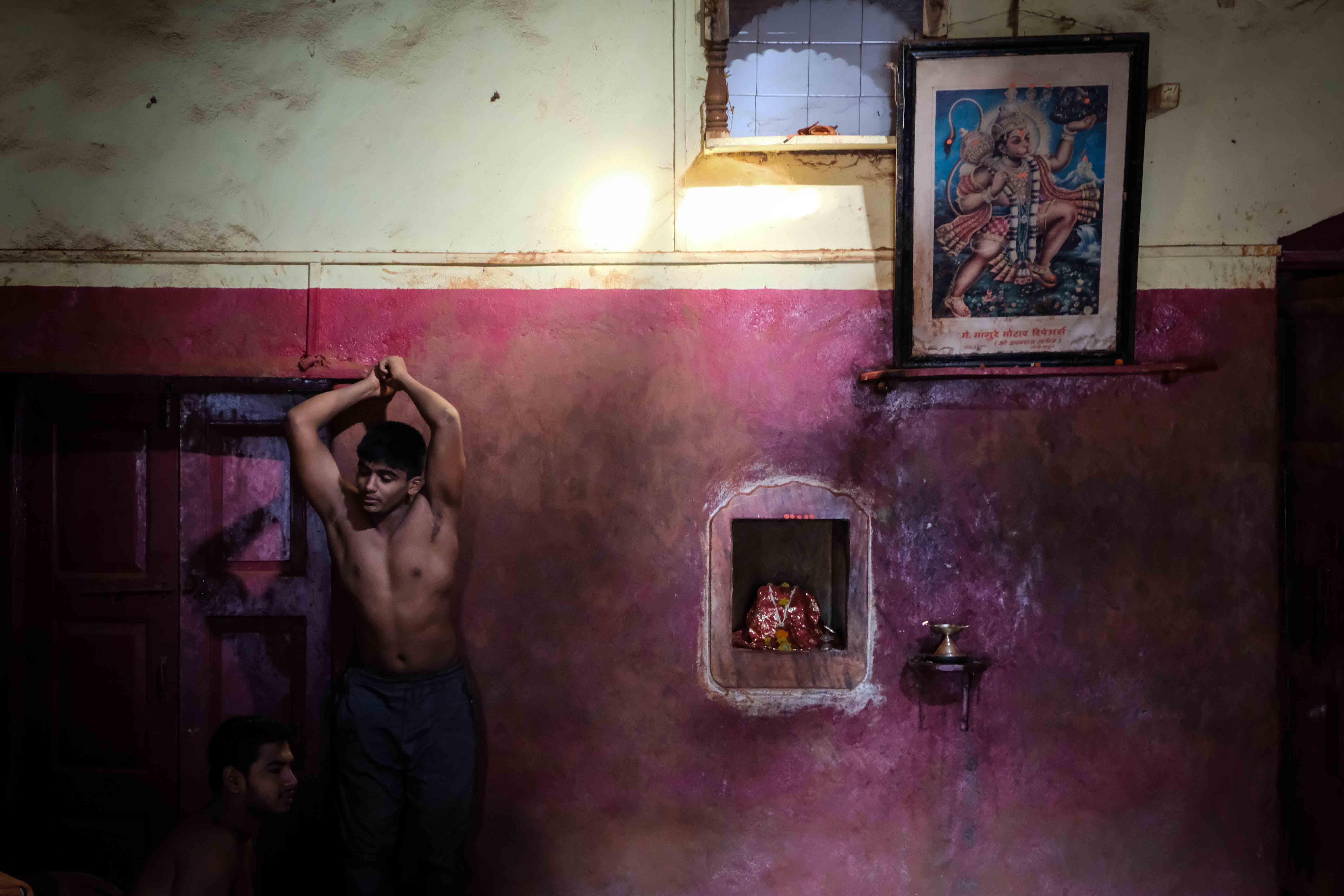 A small shrine and a big painting of Lord Hanuman hang on the walls of Gangavesh Akhara. Hanuman is idolised by all wrestlers for his immense strength, celibate lifestyle and complete dedication to serving Lord Rama. Pehelwans try to emulate these traits of Hanuman in their own morals, personality and training. Photograph by Indrajit Khambe ©Sahapedia