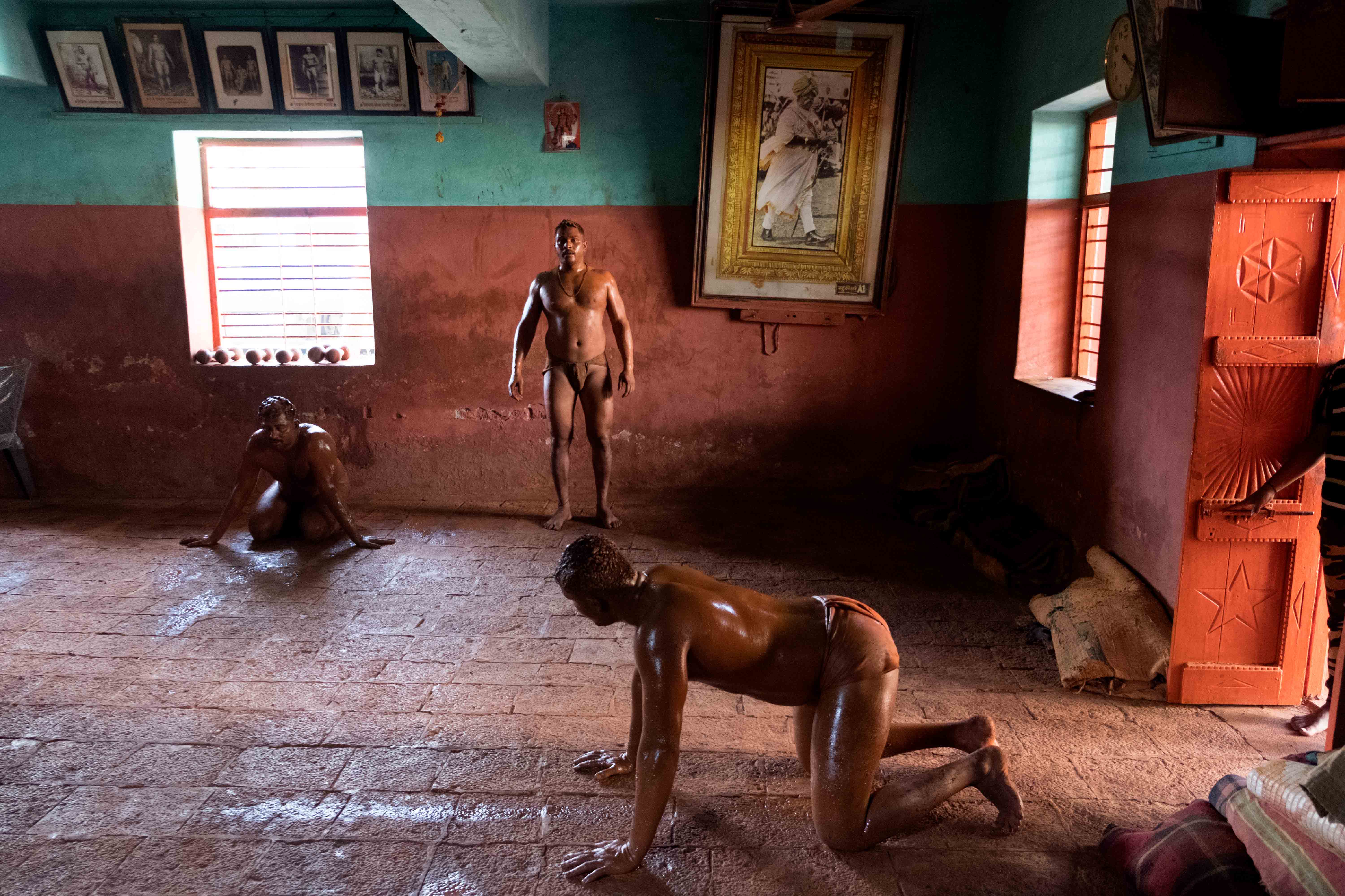 Wrestlers warming up in Shahupuri Akhara in front of a large portrait of Chhatrapati Shahu Maharaj, the King of Kolhapur who is credited with popularising wrestling in his princely state. Photograph by Indrajit Khambe ©Sahapedia 