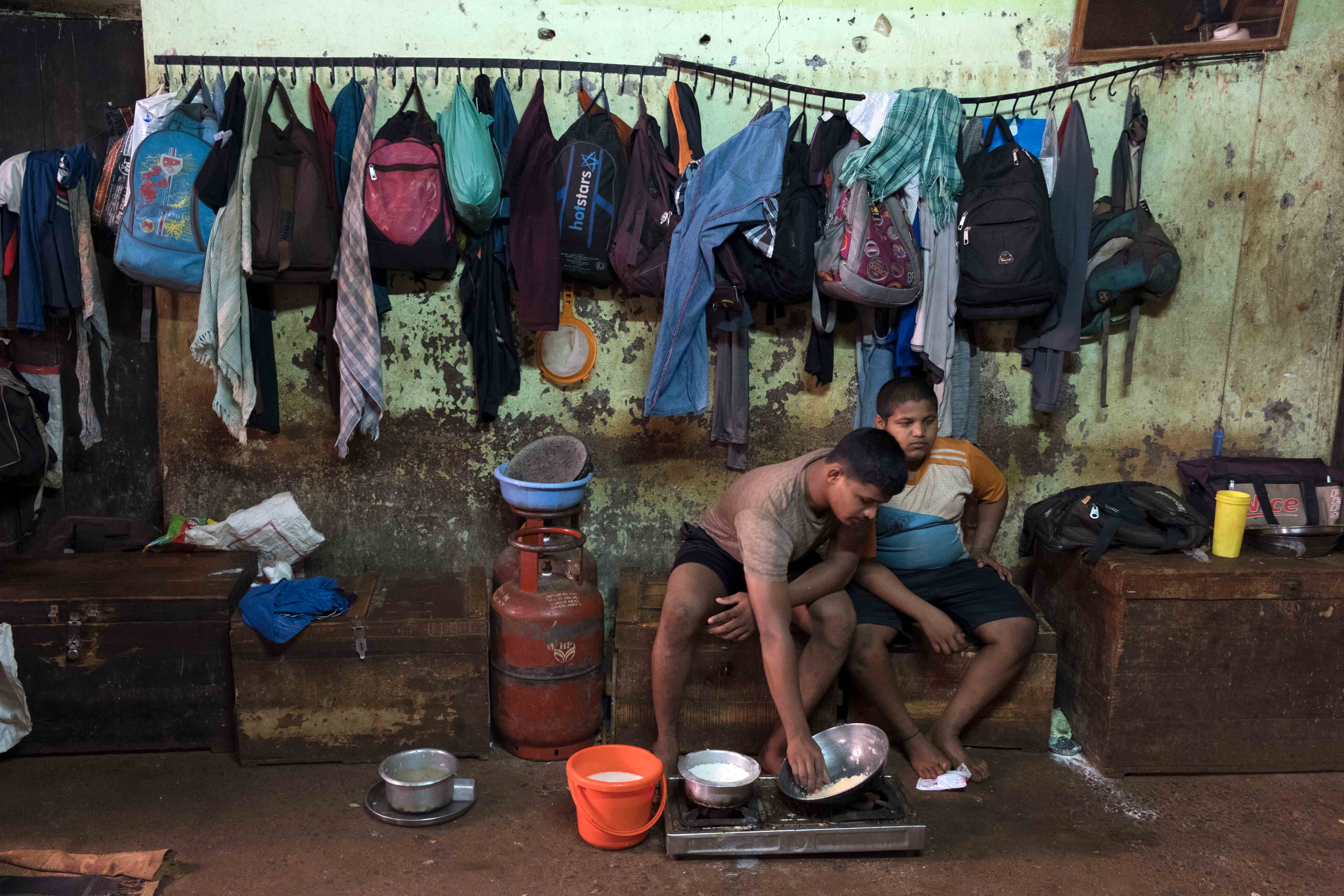 Scene from living area of Gangavesh Taleem where two wrestlers are making their breakfast. Demarcation of space and privacy are both luxuries in the akharas and often the same space serves different purposes. Seen in the photo are wrestlers cooking in the area which is alternately used as a space for sleeping and as a changing room. Photograph by Indrajit Khambe ©Sahapedia