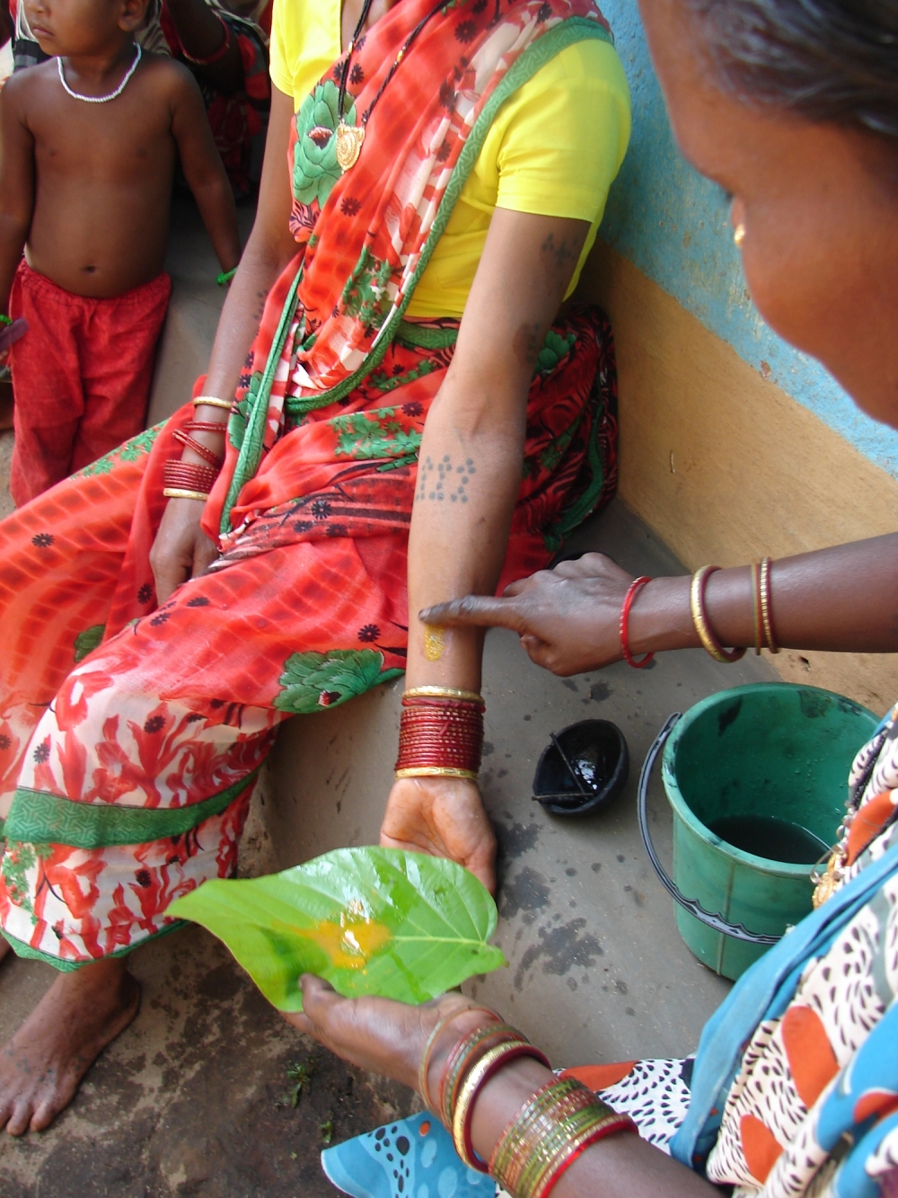 applying cowdung and turmeric paste on the newly etched godna