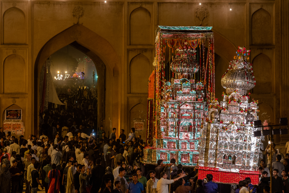 Fig. 9: People at Shahi Juloos to witness the Shahi Zarih of Hussainabad Allied Trust at Rumi Gate in Lucknow. The zarih layered with wax (left) is accompanied by a smaller bamboo taziya layered with arbak