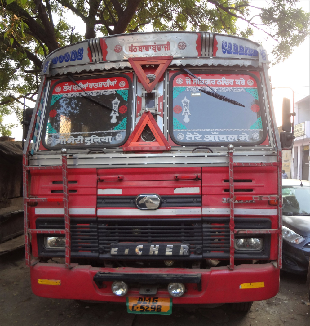 Fig. 2: The script of truck literature depends on the linguistic identity of the truck driver or the owner. One of the most common themes of truck literature in North India is the invocation of gods and one’s parents. Also striking in this photo is that the truck is much less decorated as compared to the trucks from other states. This has to do with strict guidelines on truck registration in Delhi, which leave little space for personal indulgence. 