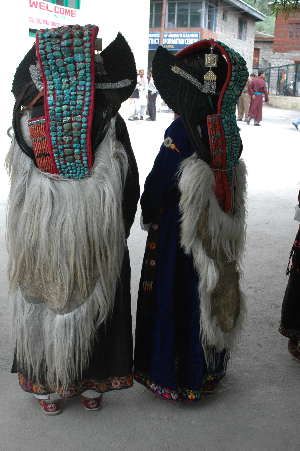 At a celebration in Kargil, two women wearing their perags (turquoise-studded headdress) along with capes made from goatskin (slog-pa) over their robes. The edges of their robes have a piping of hand-embroidered floral motifs, common in the region (Photographer: Monisha Ahmed, 2005)