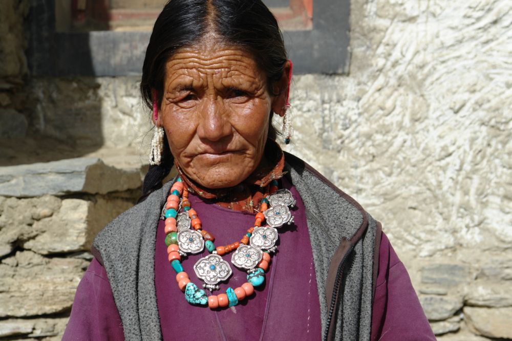 The woman shown here is wearing two necklaces—one consists of a series of eight silver amulets, strung together on a strand of coral beads, with a central turquoise stone. The second necklace consists of large coral and turquoise stones. In her ears she is wearing several strands of pearls with a small turquoise and coral stone on either side, at the end. A loop of red yarn around her ears takes the weight off the hole in her ear. (Photographer: Monisha Ahmed, 2007)