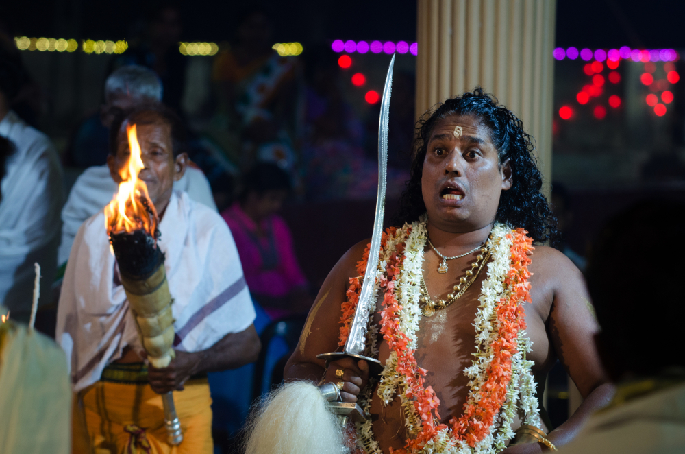 Fig 1: A paatri delivering nudi (his address) during bhootakola. The nudi is rapidly spoken by the paatri as he impersonates the bhoota; the message is not easily understood unless the listener is an expert of ancient Tulu. Commonly, the nudi consists of phrases that translate to convey that the bhoota/daiva is watching over the village, that he sees the good and bad and delivers justice, that he’s happy or angry about certain events of the village, and he needs things to go a certain way. The guttu owner answers him and promises to carry out his commands