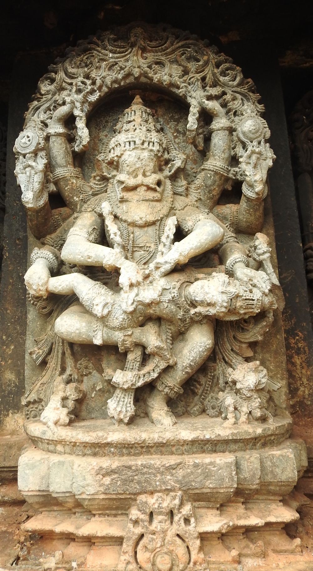 Fig. 12: A panel on the jangha shows demon Hiranyakashyapa approaching from left, Vidaraka Narasimha killing the demon by ripping open his stomach and pulling out his intestines, and Pralhada standing on the right in anjalimudra.