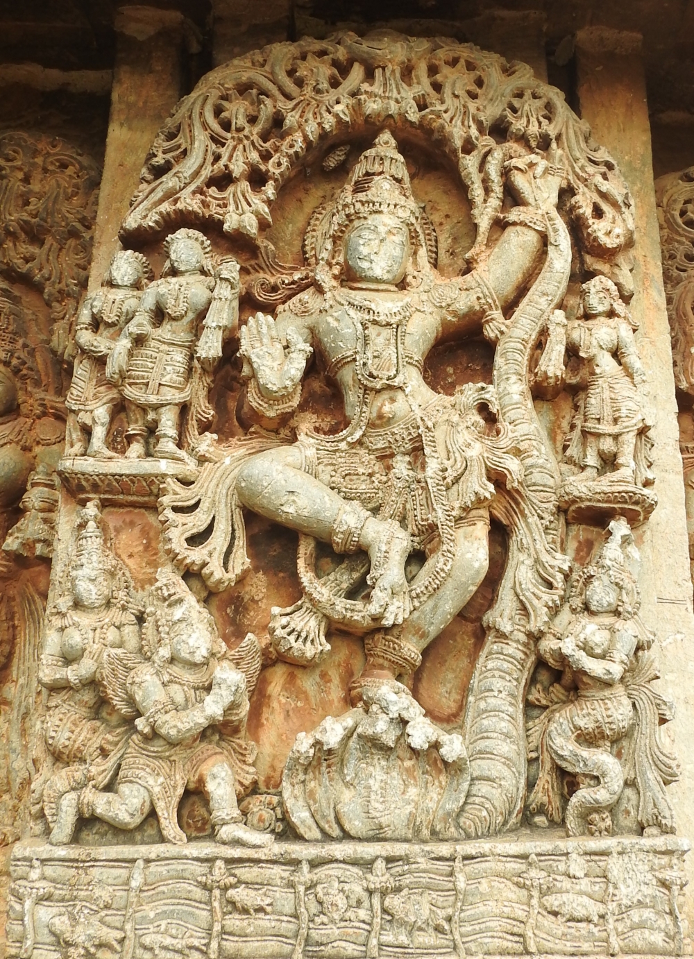 Fig. 14: The Kaliyamardana episode from Krishna’s life displayed on the jangha. He is shown dancing on the head of the five-hooded Kaliya while Kaliya’s wives and Garuda are seen in anjalimudra. The Yamuna river, where this episode takes place is carved as well with minute detailing such as waves from river, fishes and turtles inside the river, and half immersed figure of Kaliya from the river