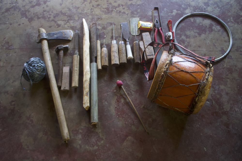 Fig. 5:  Nkhuangh, viewed from the top, with the tools required for its construction. These iron tools are required for carving and hollowing out the dense wood and giving it a drum shape (Courtesy: R. Husuang)