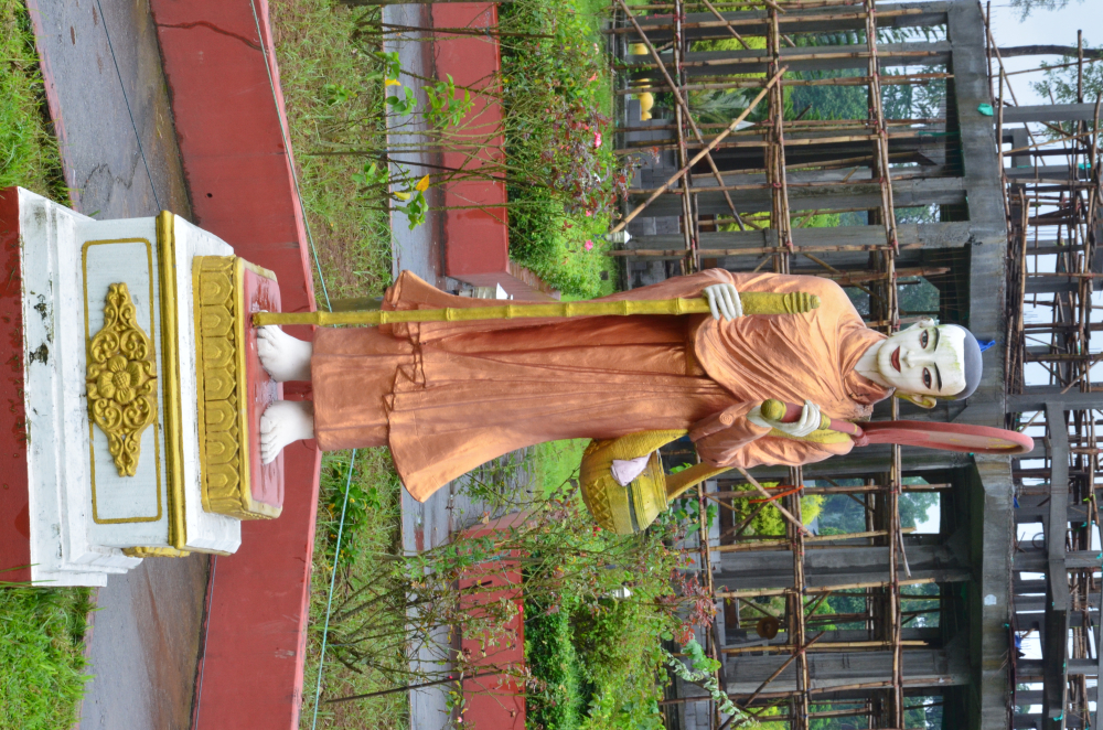 Fig.6: A large sculpture of Sivali in Kongmu Kham (golden pagoda monastery), Tengapani, Arunachal Pradesh. A disciple of the Buddha, Sivali is the patron saint of travel and harbinger of fortune. In his images, he is represented as a travelling monk. He holds a walking staff, an alms bowl, and a shade for protection from the sun