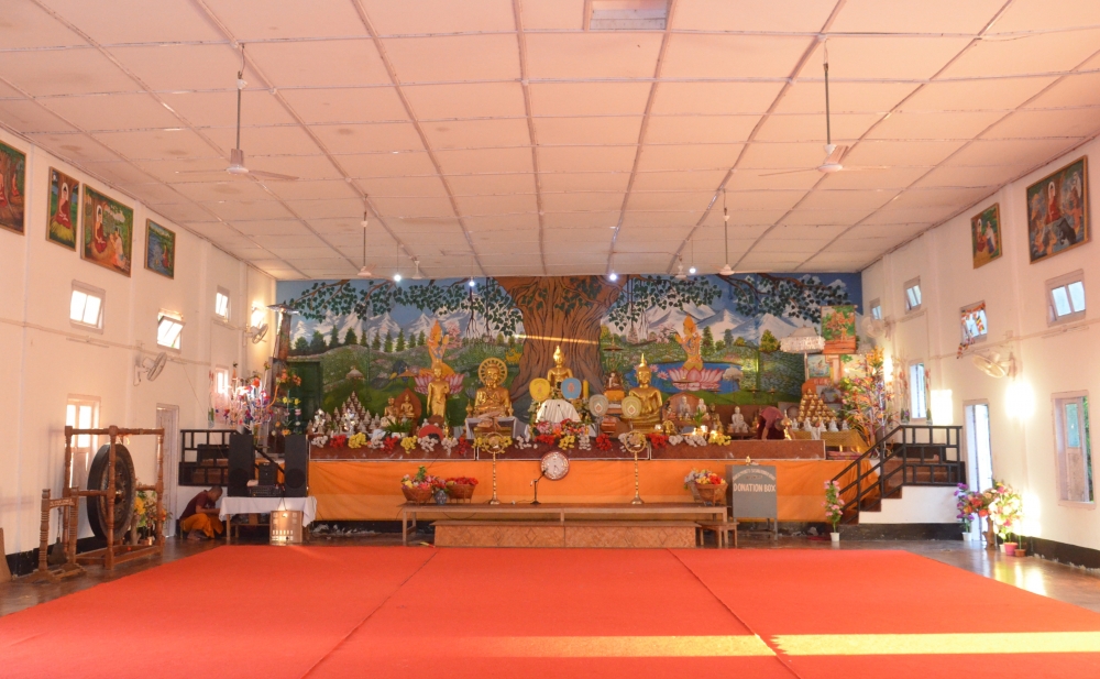 Fig. 3: The prayer hall of Pariyatti Sasana Buddha Vihar, Namsai, Arunachal Pradesh. A prayer hall is the most important place in the monastery. Multiple images of the Buddha are kept on an altar at the extreme end of the prayer halls; the background of this altar is decorated with paintings of celestial beings, natural scenery, and ornamental motifs (Courtesy: Ajanta Das)