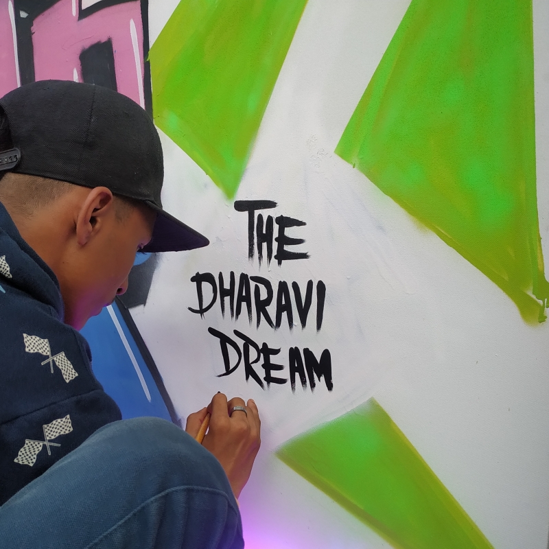 Pranay (Sketchy Artist), a graffiti artist from Dharavi, finishing a graffiti with the signature of his institute, the Dharavi Dream Project (Courtesy: Goutham Raj Konda)