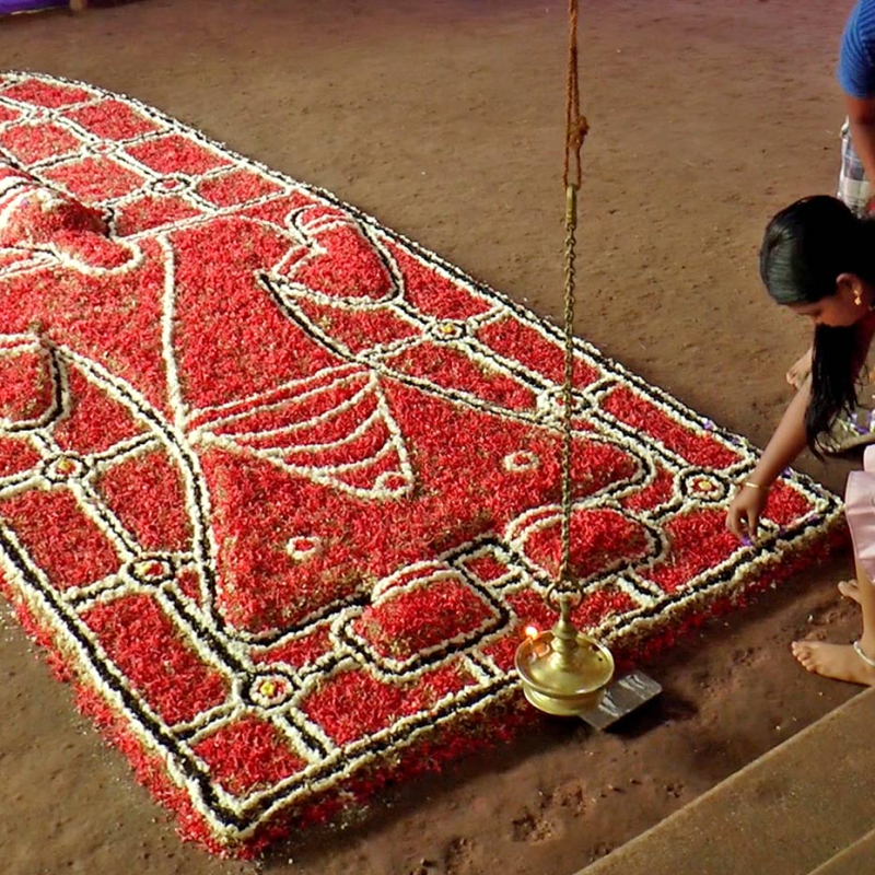 Young girls creating figure of Kama with flowers  