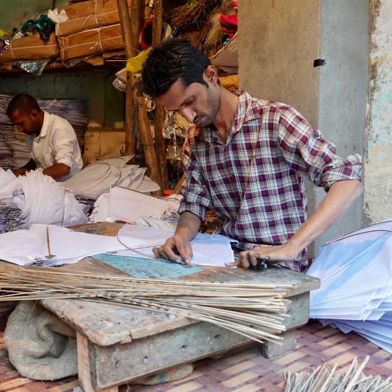 Attaching bamboo sticks along the kite edges to prevent tearing and add stiffness (Courtesy: Ashna Patel)